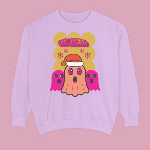 A holiday sweatshirt featuring a cute ghost character wearing a Santa hat, with two smaller ghosts on either side. Above them is the playful text "Boo Humbug," surrounded by snowflakes and festive elements. The design humorously combines spooky and festive themes for a unique holiday look.